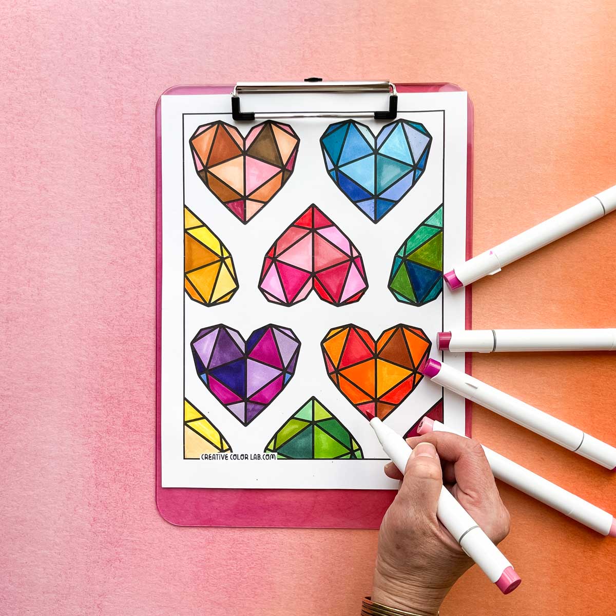 Heart coloring page being filled in with a hand holding a marker.